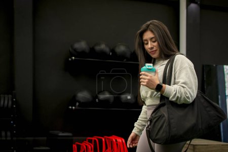 Photo for Female athlete arriving at the gym with her sports bag and shaker to do her weight training. - Royalty Free Image