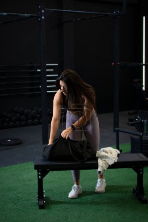 Foto de Atleta buscando a través de su mochila mientras se prepara para entrenar en el gimnasio. - Imagen libre de derechos