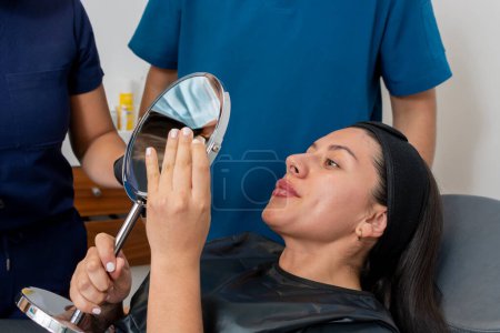Young woman observes her lips after receiving a botox treatment