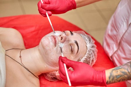 Girl with a cream mask on her face. Facial massage with brushes
