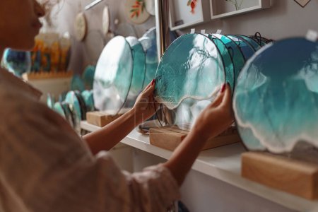 Foto de Las manos decoradoras femeninas colocan bandeja de resina epoxi hecha a mano en la exposición del soporte. Foto de alta calidad - Imagen libre de derechos