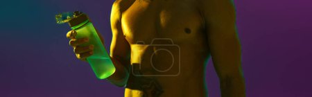 Sporty man with muscled naked torso holding bottle with water on studio background with color filter Poster 646464732