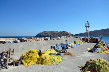 Foto de Greece, Crete, mole with fishing nets and boats in the port of Plaka with the fortress of Spinalonga, a former leper colony - Imagen libre de derechos