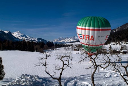 Photo for Hochfilzen, Austria - January 26, 2009: Landing of a hot air balloon on a snow-covered meadow in Tyrol in background panaorama of Austrian Alps with Kitzbueheler Horn - left and Wilder Kaiser - middle - Royalty Free Image
