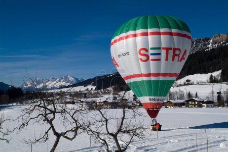 Photo for Hochfilzen, Austria - January 26, 2009: support by landing of a hot air balloon on a snow-covered meadow in Tyrol and Wilder Kaiser Mountain in background, - Royalty Free Image