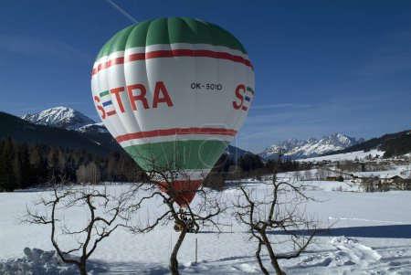 Photo for Hochfilzen, Austria - January 26, 2009: Landing of a hot air balloon on a snow-covered meadow in Tyrol in background panaorama of Austrian Alps and Wilder Kaiser Mountain - Royalty Free Image