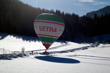 Photo for Hochfilzen, Austria - January 26, 2009: support by landing of a hot air balloon on a snow-covered meadow in Tyrol - Royalty Free Image