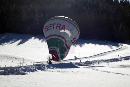 Photo for Hochfilzen, Austria - January 26, 2009: support by landing of a hot air balloon on a snow-covered meadow in Tyrol - Royalty Free Image