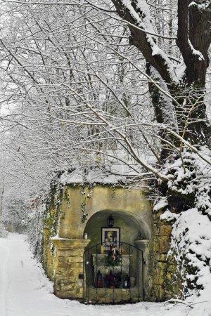 Austria, santuario junto al camino en el bosque caducifolio cubierto de nieve profunda de la reserva natural de Mannersdorf Wueste