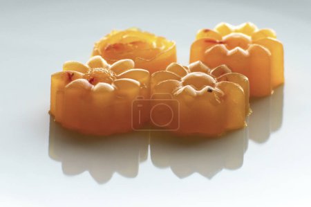 Photo for Close up shot of four vegan orange and saffron flower shaped agar jellies - Royalty Free Image
