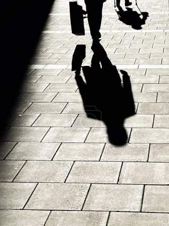 Photo for Shadow of man and old lady walking in the sun - Royalty Free Image