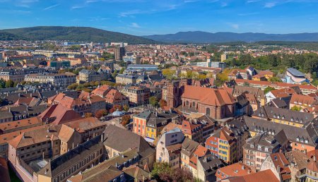 Foto de View of the historical part of the city of Belfort with a fortress, tiled roofs of houses, a cathedral and mountains in the background. Belfort, France - September 2022 - Imagen libre de derechos