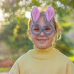 a smiling little girl in a glasses with rabbit ears in the garden. Easter bunny funny costume