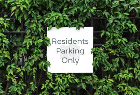 Parking pour les résidents seulement signer sur la clôture parmi les feuilles de la brousse