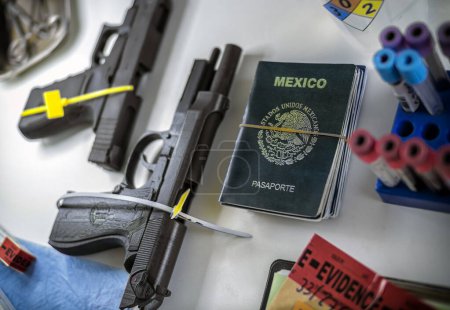Téléchargez les photos : Plusieurs armes à feu à côté du passeport mexicain en laboratoire de la criminalité, imag conceptuel - en image libre de droit