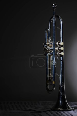 Téléchargez les photos : Vue de l'instrument de musique qui est la trompette sur le fond de la partition - en image libre de droit