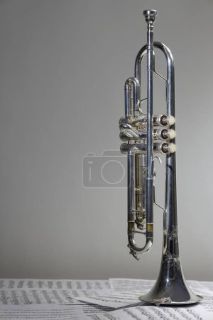 Téléchargez les photos : Vue de l'instrument de musique qui est la trompette sur le fond de la partition - en image libre de droit