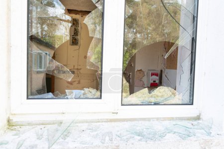 Photo for Detail of room interior in abandoned Hospital derelict with hand sanitiser dispenser visible through smashed window. - Royalty Free Image