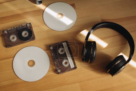 Foto de Discos compactos, casetes con auriculares en una mesa de madera. Burla.. - Imagen libre de derechos