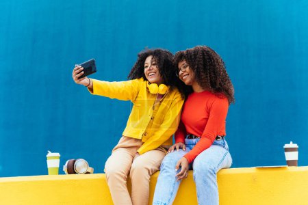 Téléchargez les photos : Les jeunes femmes heureuses qui prennent des selfies avec le smartphone. Les adolescents s'amusent en plein air après l'école - en image libre de droit