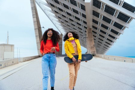 Foto de Jóvenes mujeres felices divirtiéndose al aire libre, riendo y compartiendo buen humor. Adolescentes niñas caminando en el puerto de Barcelona después de la escuela - Imagen libre de derechos