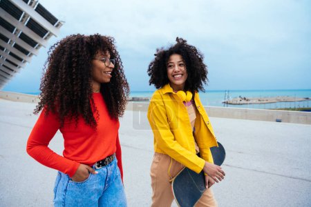 Foto de Jóvenes mujeres felices divirtiéndose al aire libre, riendo y compartiendo buen humor. Adolescentes niñas caminando en el puerto de Barcelona después de la escuela - Imagen libre de derechos