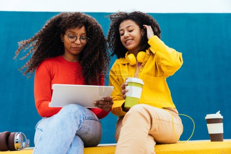 Téléchargez les photos : Jeunes femmes heureuses étudiant sur un appareil tablette. les adolescents passent du temps ensemble après l'école - en image libre de droit