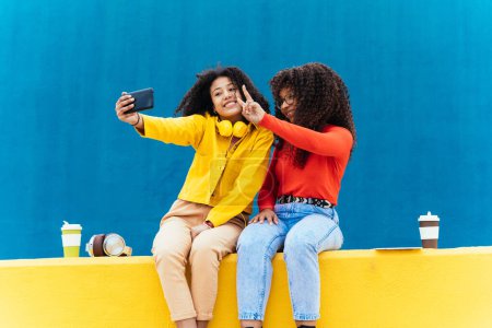 Photo for Young happy women taking selfies with the smartphone. Teenagers having fun outdoor after school - Royalty Free Image