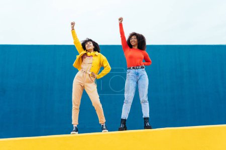 Foto de Mujeres jóvenes felices posando en paredes de color azul y amarillo. Adolescentes chica pasar tiempo juntos después de la escuela - Imagen libre de derechos