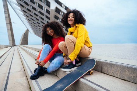 Téléchargez les photos : Jeunes femmes heureuses s'amusant en plein air, riant et partageant la bonne humeur. Adolescentes assises au port de Barcelone après l'école - en image libre de droit