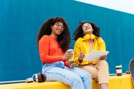Téléchargez les photos : Jeunes femmes heureuses étudiant sur un appareil tablette. les adolescents passent du temps ensemble après l'école - en image libre de droit