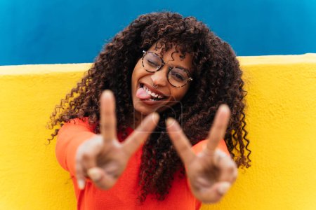 Photo for Young happy woman smiling and having fun outdoor. Teenager girl with curly hair posing and making happy face expressions in front the camera - Royalty Free Image