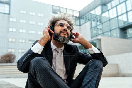 Photo for Young entrepreneur business man listening to music and dancing outside the office. Concept about freedom and success in business - Royalty Free Image