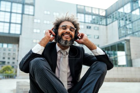 Photo for Young entrepreneur business man listening to music and dancing outside the office. Concept about freedom and success in business - Royalty Free Image