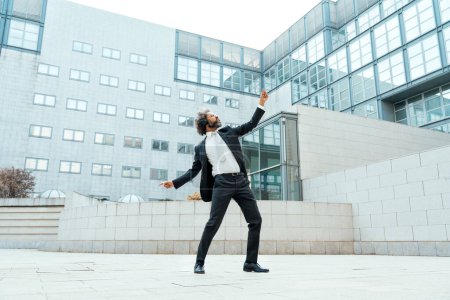 Foto de Joven empresario hombre de negocios escuchando música y bailando fuera de la oficina. Concepto sobre libertad y éxito en los negocios - Imagen libre de derechos