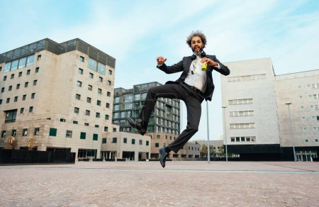 Foto de Joven emprendedor saltando y bailando para celebrar su exitoso día en el trabajo. Concepto de libertad y despreocupación en la carrera empresarial - Imagen libre de derechos