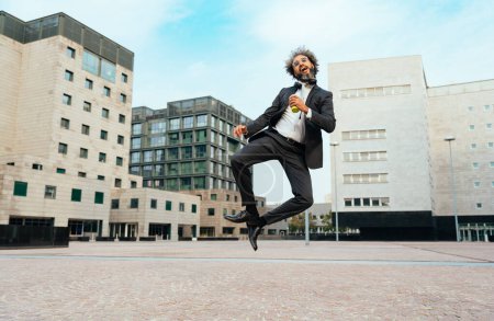 Foto de Joven emprendedor saltando y bailando para celebrar su exitoso día en el trabajo. Concepto de libertad y despreocupación en la carrera empresarial - Imagen libre de derechos