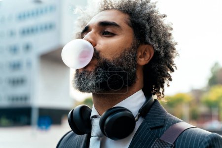 Téléchargez les photos : Jeune entrepreneur mâcher de la gomme à bulles de fruits et faire des ballons - en image libre de droit