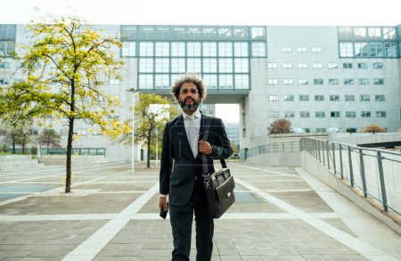 Téléchargez les photos : Jeune entrepreneur homme d'affaires marchant devant son bureau après une journée bien remplie de travail réussi - en image libre de droit