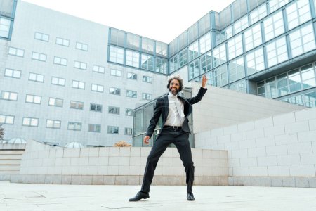 Foto de Joven empresario hombre de negocios escuchando música y bailando fuera de la oficina. Concepto sobre libertad y éxito en los negocios - Imagen libre de derechos