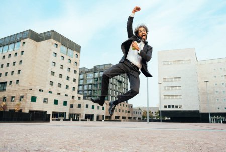 Photo for Young entrepreneur jumping and dancing to celebrate his successful day at work. Concept about freedom and carefree in business career - Royalty Free Image