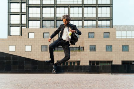 Téléchargez les photos : Jeune entrepreneur sautant et dansant pour célébrer sa journée réussie au travail. Concept de liberté et d'insouciance dans la carrière professionnelle - en image libre de droit