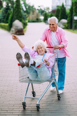 Foto de Vieja pareja moderna vestirse ropa de colores de moda. La abuela joven y el abuelo se divierten al aire libre y se vuelven salvajes. Representación de ancianos sintiéndose jóvenes por dentro - Imagen libre de derechos
