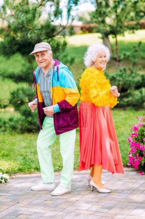 Altes modernes Paar kleidet modische farbige Kleidung. Die jugendliche Oma und der Opa haben Spaß im Freien und toben sich aus. Vertretung älterer Menschen, die sich im Inneren jung fühlen