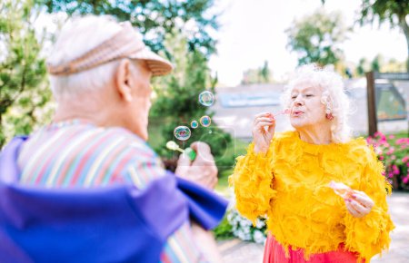 Photo for Old modern couple dressing fashionable colored clothes. Youthful grandmother and grandfather having fun outdoor and going wild. Representation of elderly people feeling young inside - Royalty Free Image