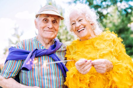 Photo for Old modern couple dressing fashionable colored clothes. Youthful grandmother and grandfather having fun outdoor and going wild. Representation of elderly people feeling young inside - Royalty Free Image