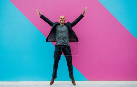 Photo for Young business man going to work in the morning passing by an urban area of the city with colored walls.Representation of a successful sales person reaching the top of the career. - Royalty Free Image
