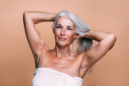 Foto de Imagen de una hermosa mujer mayor posando en una sesión de fotos de belleza. Mujer de mediana edad sobre un fondo de color. Concepto sobre positividad corporal, autoestima y aceptación corporal - Imagen libre de derechos