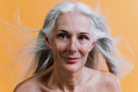 Image d'une belle femme âgée posant sur une séance photo de beauté. Femme d'âge moyen sur un fond coloré. Concept sur la positivité du corps, l'estime de soi et l'acceptation du corps