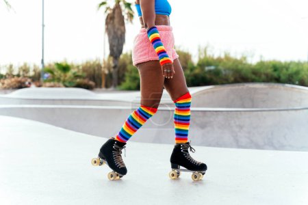 Foto de Hermosa mujer patinando con patines y divirtiéndose. Entrenamiento profesional de patinador y bailarín por la mañana con ropa de colores y de moda. - Imagen libre de derechos